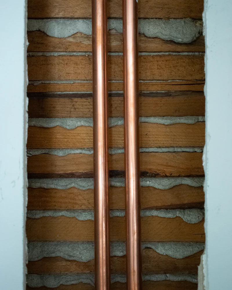 Caños de cobre instalados sobre una pared de ladrillo