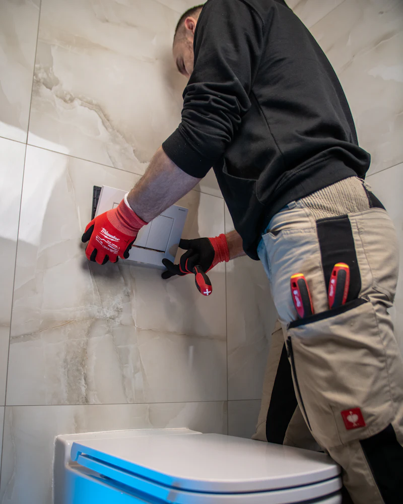Plomero con guantes trabajando en la instalación de un inodoro